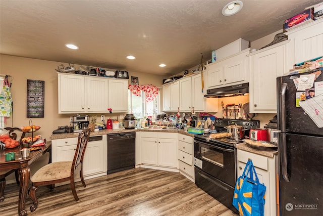 kitchen with wood-type flooring, white cabinets, black appliances, and sink