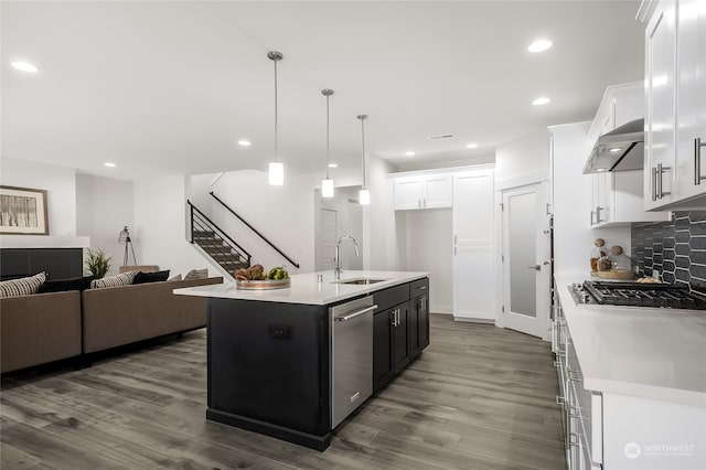 kitchen featuring stainless steel appliances, sink, decorative light fixtures, a center island with sink, and white cabinets