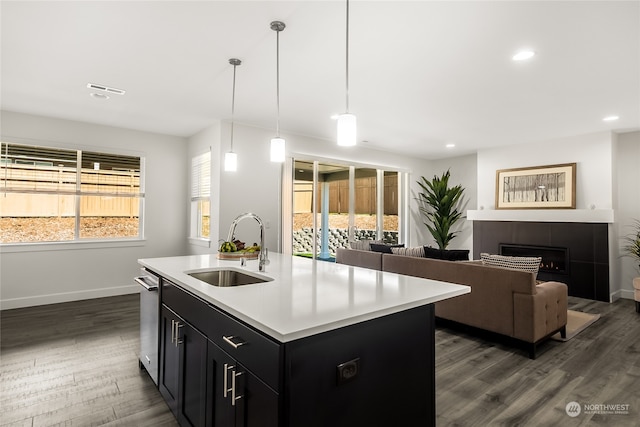 kitchen with decorative light fixtures, a healthy amount of sunlight, sink, and a kitchen island with sink