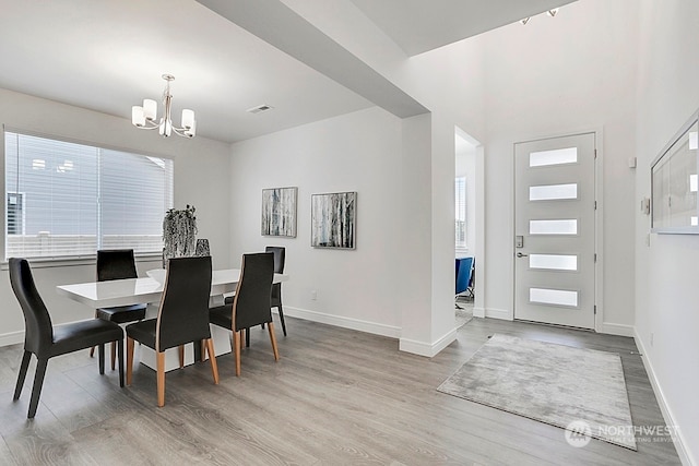 dining space featuring plenty of natural light, light hardwood / wood-style floors, and an inviting chandelier