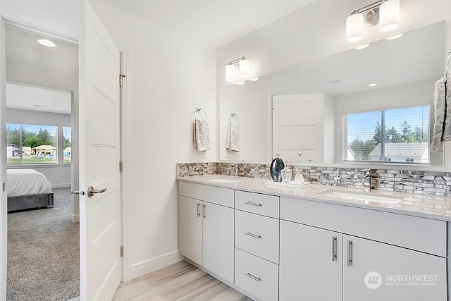 bathroom with hardwood / wood-style flooring, decorative backsplash, a healthy amount of sunlight, and vanity