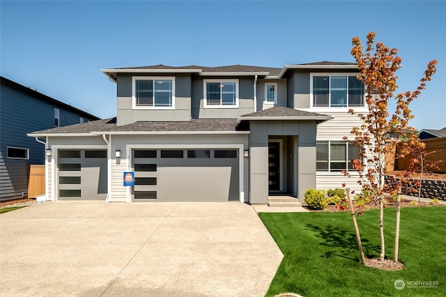 prairie-style house featuring a garage and a front lawn