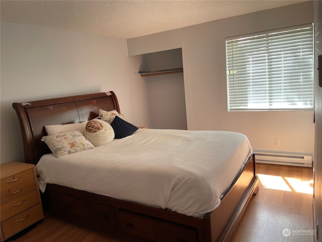 bedroom featuring a textured ceiling, a baseboard radiator, and hardwood / wood-style flooring