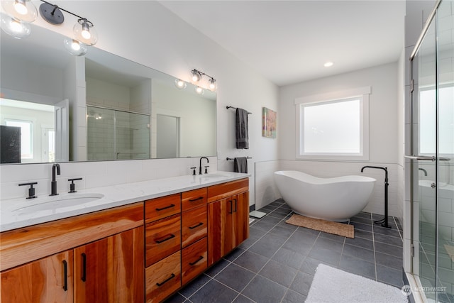 bathroom featuring dual bowl vanity, tile flooring, a wealth of natural light, and independent shower and bath