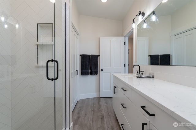 bathroom with backsplash, hardwood / wood-style flooring, a shower with shower door, vanity, and lofted ceiling