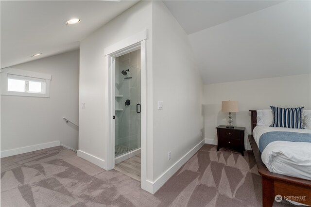 bedroom with vaulted ceiling, ensuite bath, and carpet floors