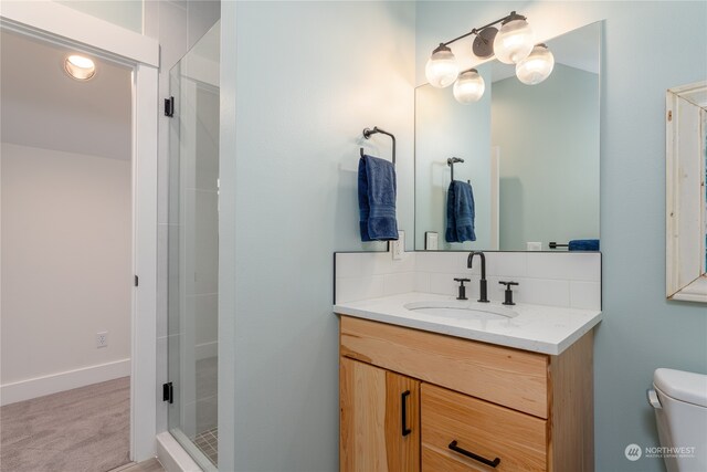 bathroom with tasteful backsplash, vanity, toilet, and a shower with door