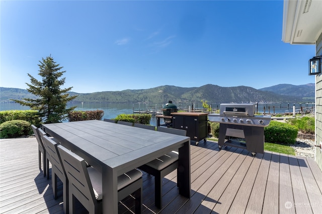 deck with a grill, a water and mountain view, and a dock