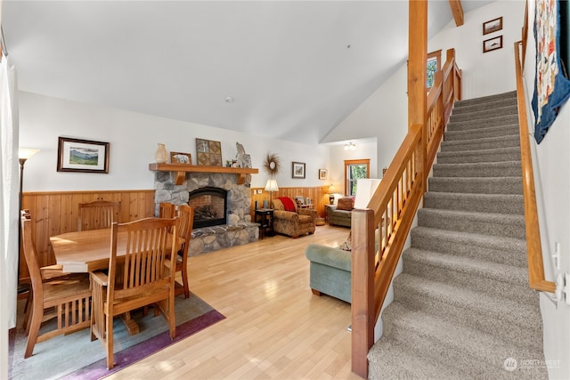 dining room with a stone fireplace, vaulted ceiling, and light hardwood / wood-style flooring