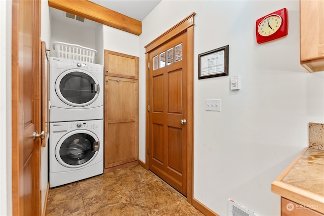 laundry room featuring cabinets and stacked washing maching and dryer