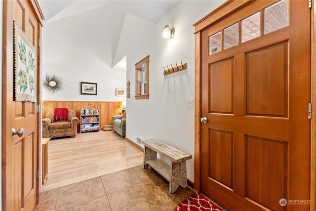 tiled foyer entrance with vaulted ceiling and wooden walls