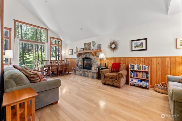 living room with a stone fireplace, high vaulted ceiling, and light hardwood / wood-style flooring