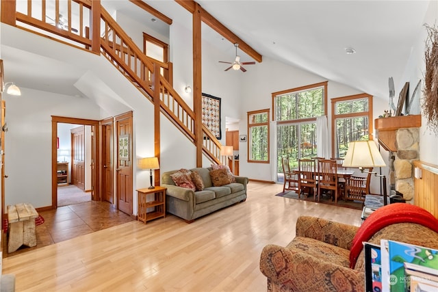 living room with beam ceiling, light hardwood / wood-style flooring, and high vaulted ceiling