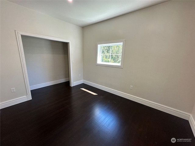 unfurnished bedroom with dark hardwood / wood-style flooring and a closet