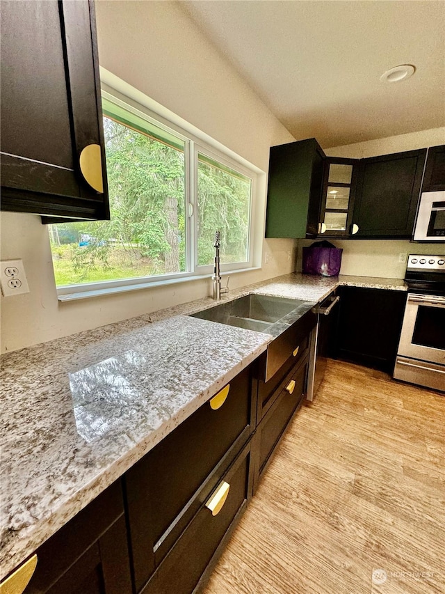 kitchen featuring light stone counters, sink, stainless steel electric range, and light hardwood / wood-style flooring