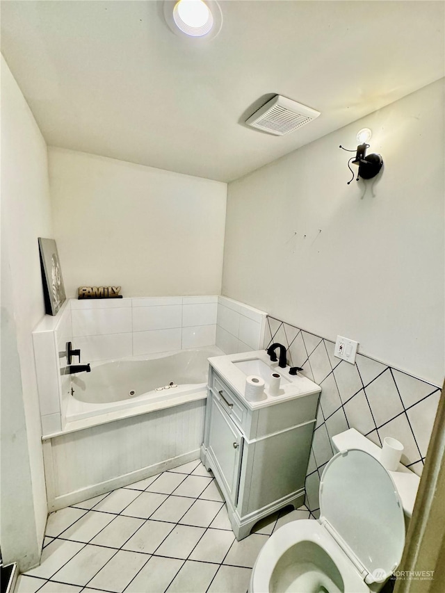 bathroom featuring a tub to relax in, tile patterned floors, toilet, tile walls, and vanity