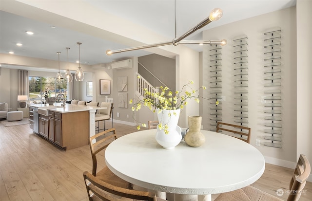 dining room with an AC wall unit, sink, and light wood-type flooring