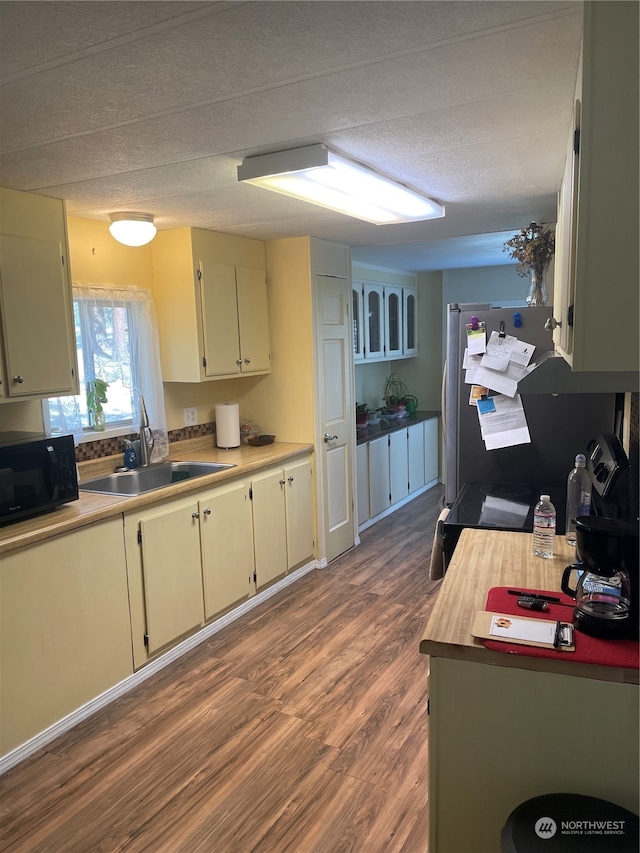 kitchen featuring cream cabinetry, a textured ceiling, hardwood / wood-style floors, and sink