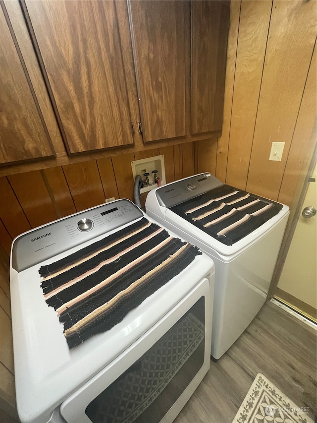 washroom featuring cabinets, independent washer and dryer, wooden walls, washer hookup, and wood-type flooring