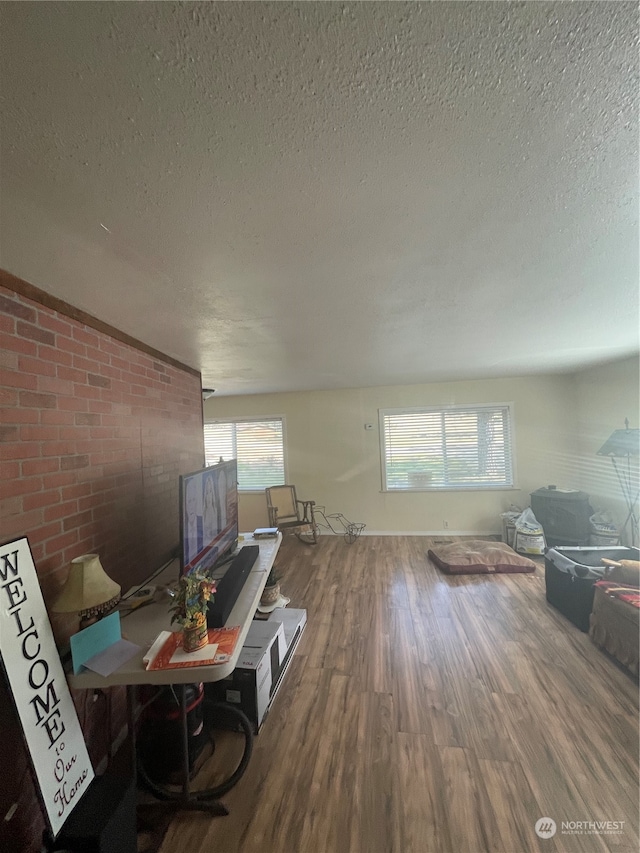 living room with a textured ceiling, hardwood / wood-style floors, and brick wall