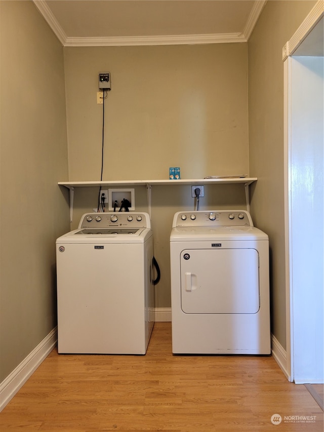 laundry room featuring washer hookup, light hardwood / wood-style flooring, crown molding, and washing machine and dryer