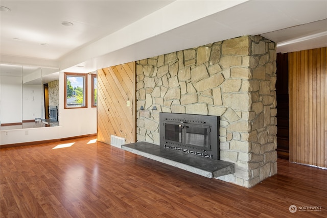 unfurnished living room with a fireplace, wooden walls, and hardwood / wood-style floors