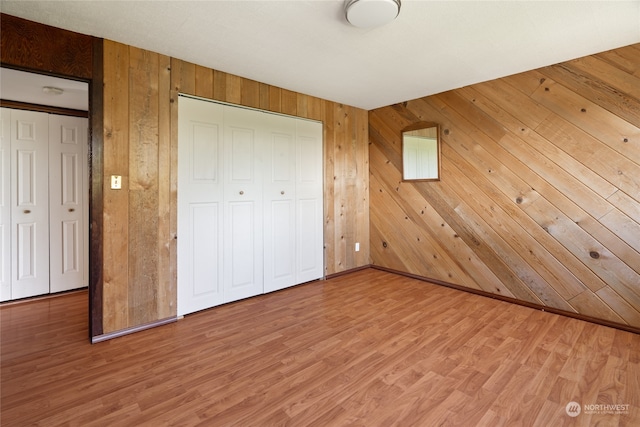 unfurnished bedroom with wood-type flooring and wooden walls