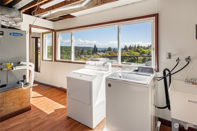 laundry room with independent washer and dryer, sink, and light hardwood / wood-style flooring