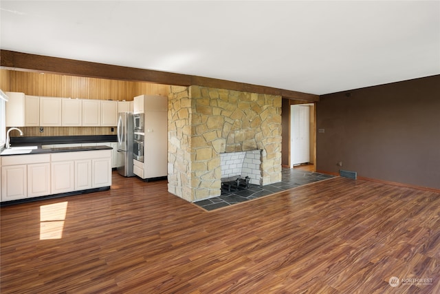 kitchen with a stone fireplace, sink, dark hardwood / wood-style flooring, and white cabinets