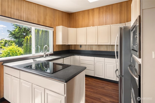 kitchen with white cabinetry, stainless steel appliances, dark hardwood / wood-style flooring, kitchen peninsula, and sink