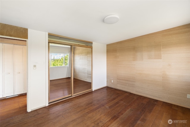 unfurnished bedroom with dark wood-type flooring and a closet