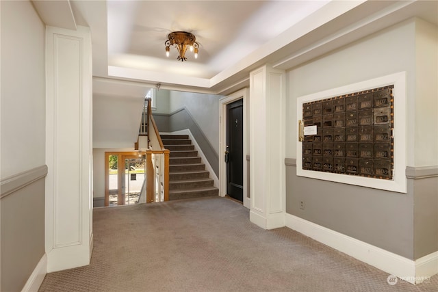 carpeted entryway with a raised ceiling