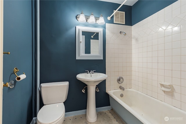 bathroom featuring tile floors, tiled shower / bath, and toilet