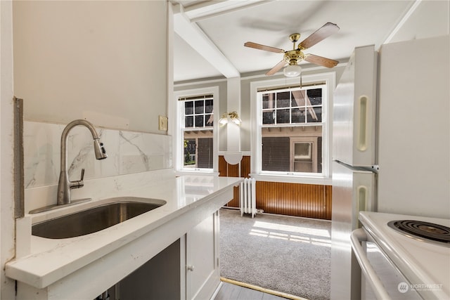 kitchen with light stone countertops, white appliances, sink, ceiling fan, and light colored carpet