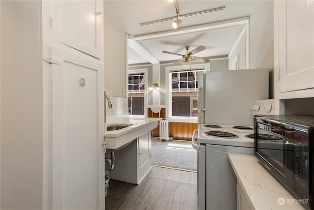 kitchen featuring light wood-type flooring, white electric range oven, white cabinets, sink, and ceiling fan