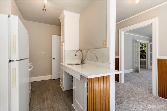 kitchen featuring white refrigerator, dark hardwood / wood-style flooring, crown molding, light stone countertops, and sink