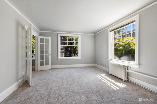 carpeted empty room featuring crown molding, a wealth of natural light, radiator heating unit, and french doors