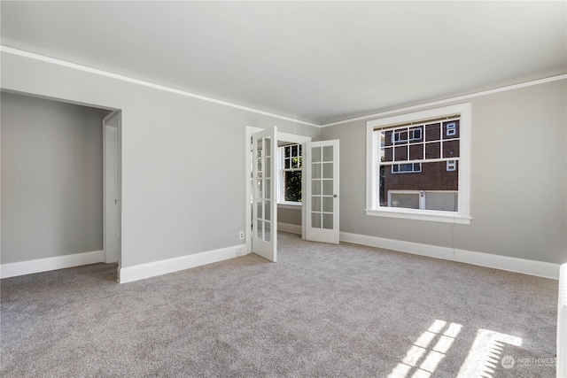 carpeted spare room featuring crown molding and french doors