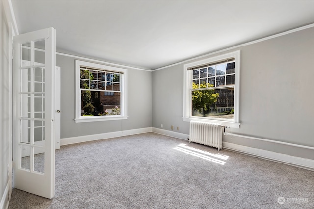 unfurnished room featuring crown molding, a wealth of natural light, carpet flooring, and radiator heating unit