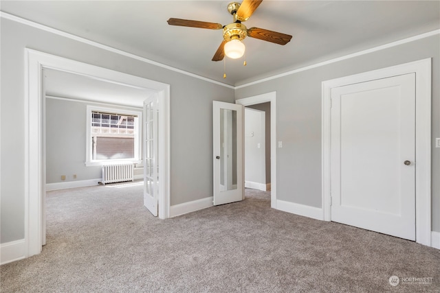 unfurnished bedroom with light carpet, crown molding, radiator, and ceiling fan