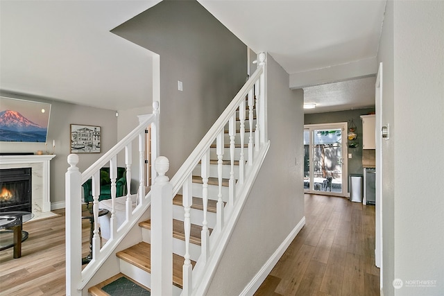 stairway featuring a premium fireplace and hardwood / wood-style flooring