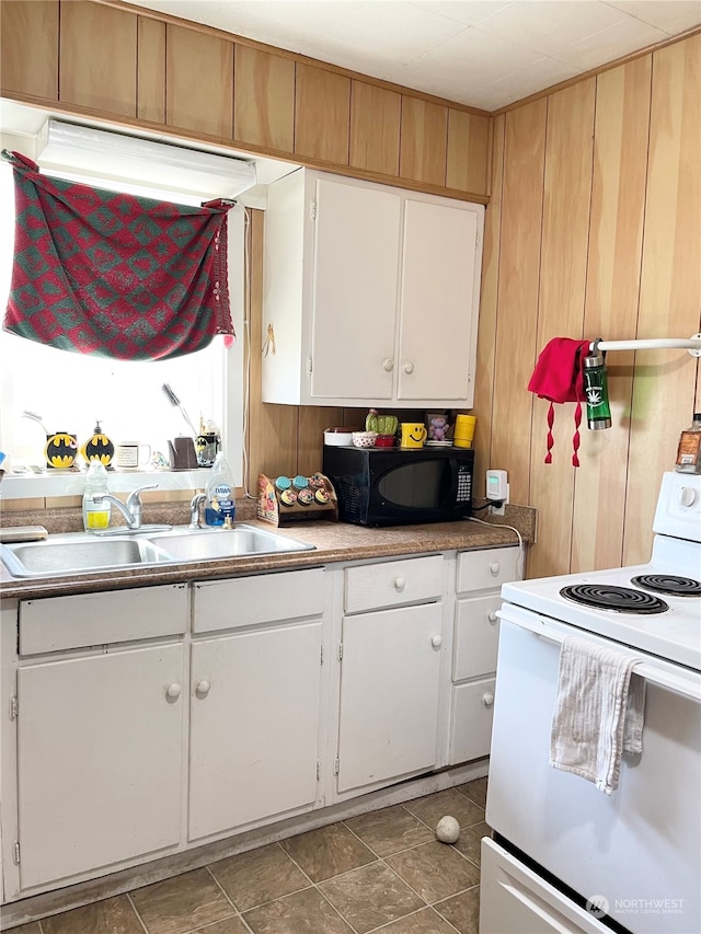 kitchen with electric range, tile floors, sink, wood walls, and white cabinetry