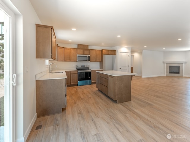 384 Emma Dr, Wenatchee, WA 98801 - kitchen with appliances with stainless steel finishes, sink, a tile fireplace, a center island, and light hardwood / wood-style floors