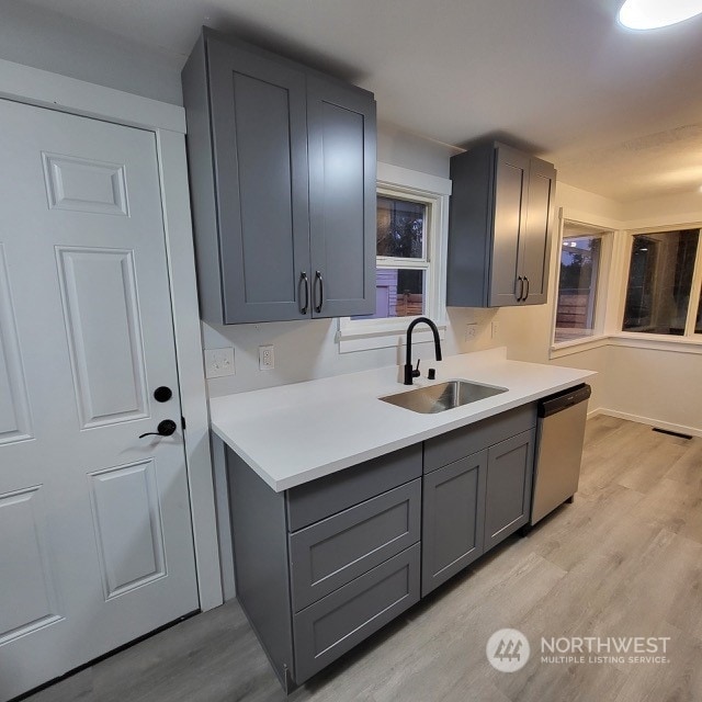 kitchen featuring light hardwood / wood-style flooring, sink, dishwasher, and gray cabinets