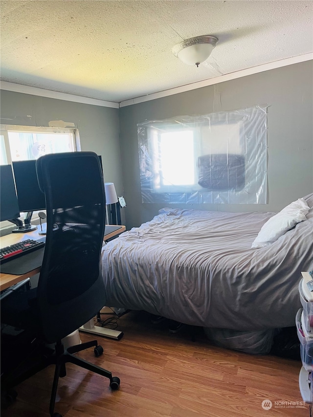 bedroom with multiple windows, hardwood / wood-style floors, and a textured ceiling