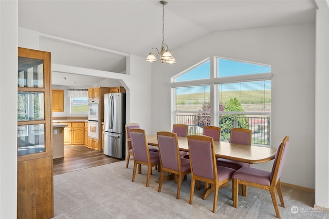 dining space featuring an inviting chandelier, light hardwood / wood-style flooring, and vaulted ceiling