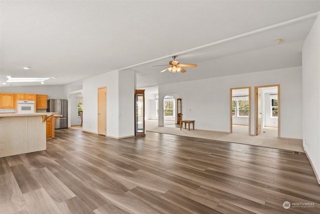 unfurnished living room with ceiling fan, a healthy amount of sunlight, and hardwood / wood-style flooring