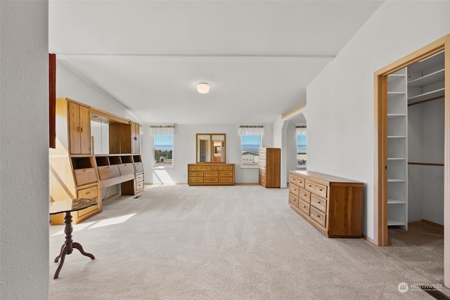 unfurnished bedroom with light colored carpet, lofted ceiling, a walk in closet, and a closet