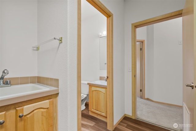 bathroom featuring wood-type flooring, vanity, and toilet