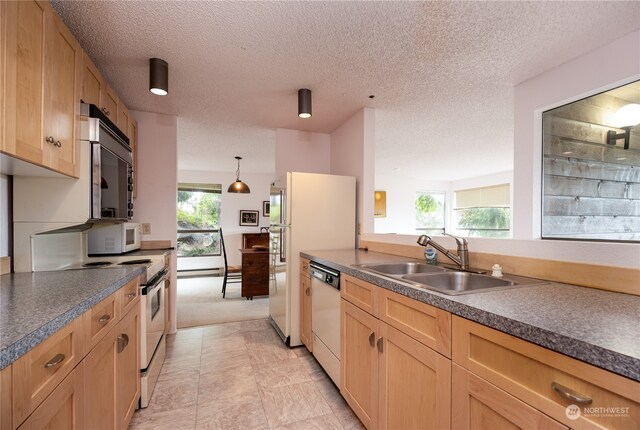 kitchen with a healthy amount of sunlight, sink, white appliances, and light tile flooring